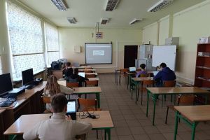 Uczniowie siedzący w sali informatycznej rozwiązują konkurs „Trzymaj formę”.